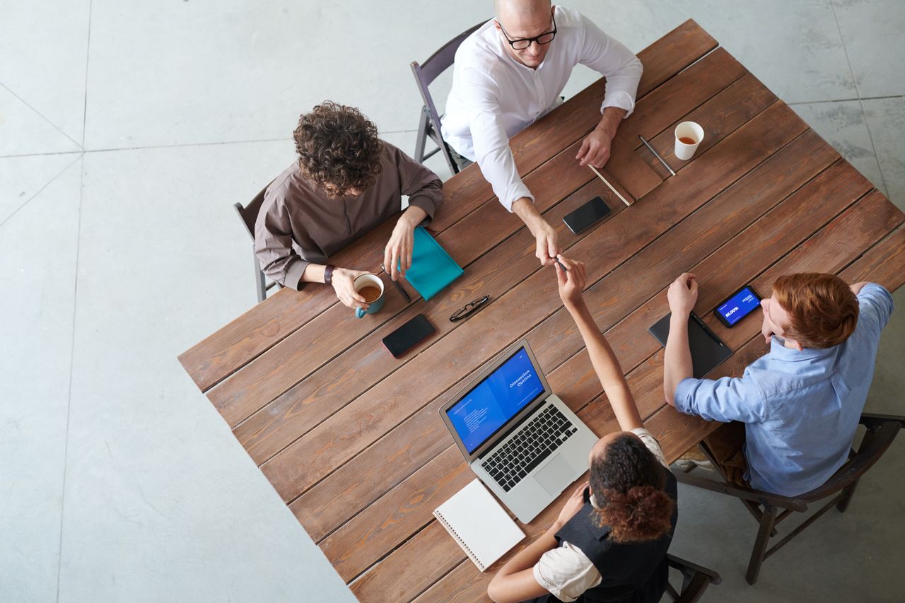 About High angle view of a collaborative team meeting in an office setting with laptops and coffee.