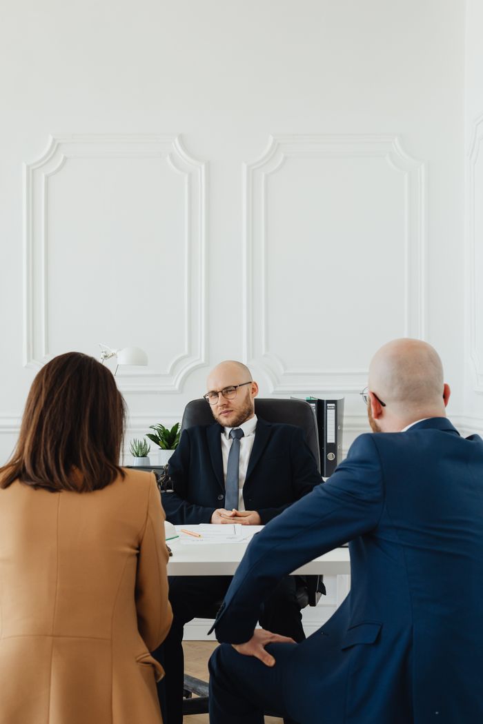 Services A lawyer consults a couple on divorce proceedings in an elegant office setting.